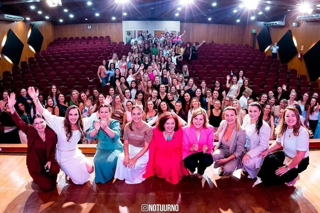 Michele Marques com um grande grupo de pessoas em um auditório